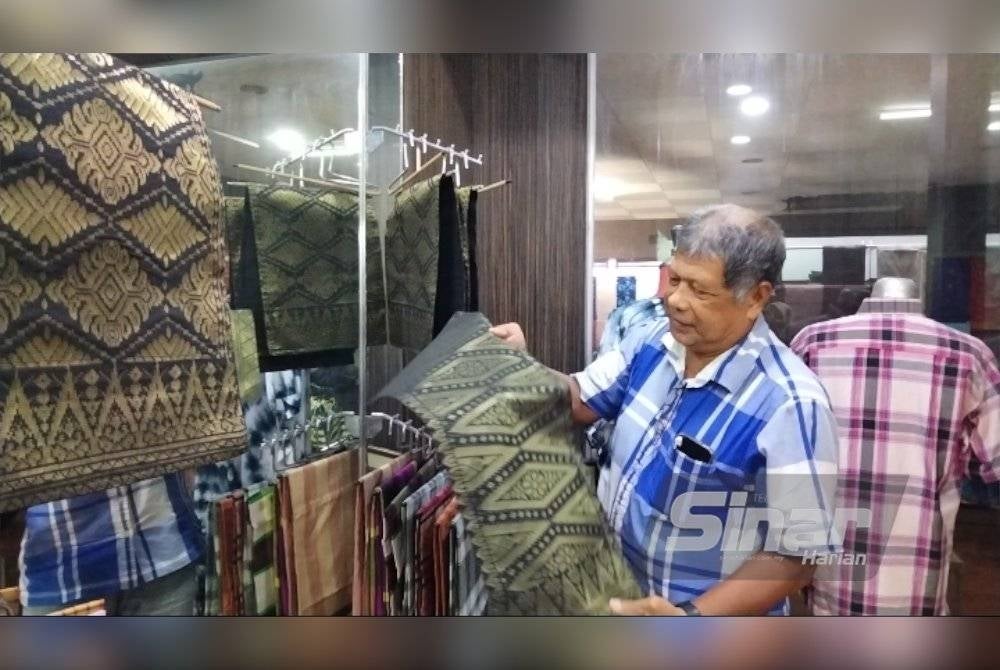 Ahmad Kamil menunjukkan alas meja kecil daripada songket.