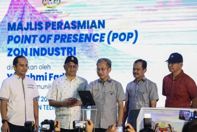 Fahmi (tengah) meletakkan tangan pada tablet sebagai simbolik perasmian PoP Zon Industri di Kampung Lapasan. - Foto Bernama
