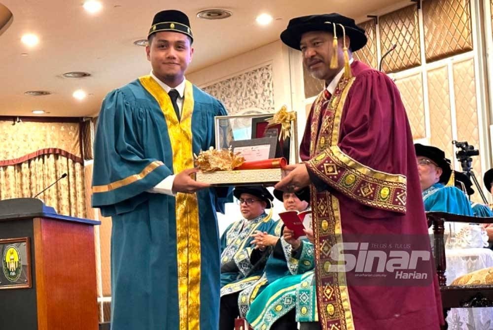 Mohd Nassuruddin (kanan) menyampaikan Anugerah Kecemerlangan Tok Pulau Melaka kepada Wan Syahmi Daniel.