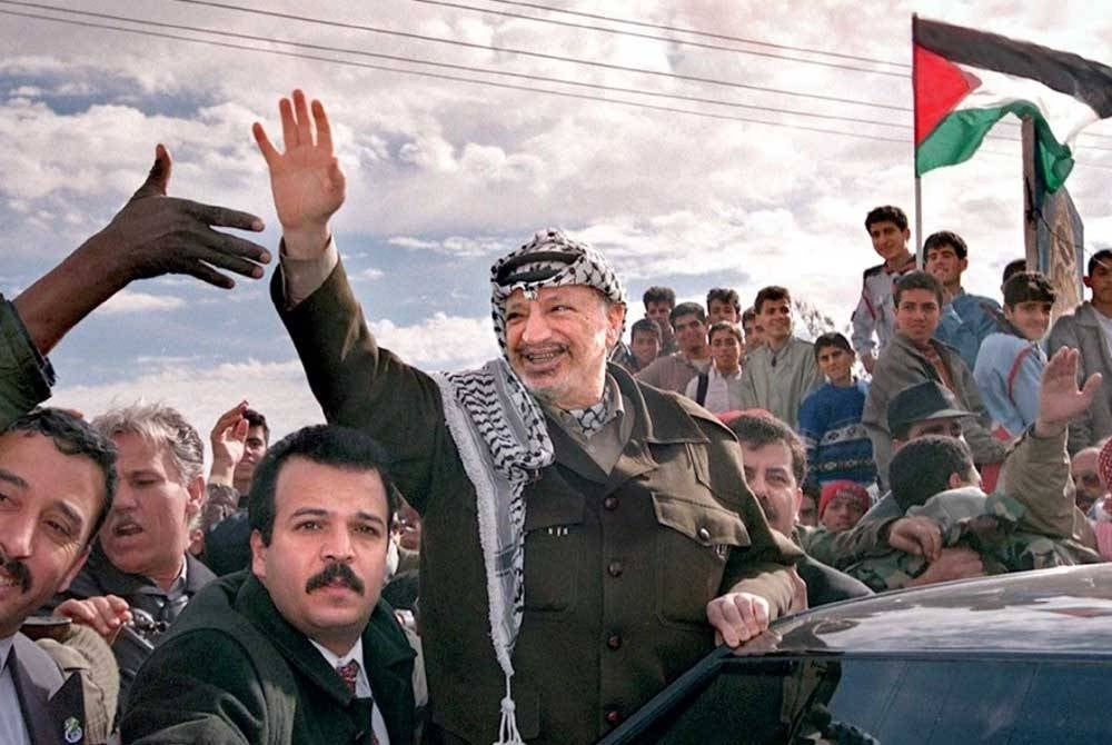 Yasser melambai ke arah penduduk Palestin di Lintasan Rafah selepas mengunjungi Genting Gaza pada Februari 1998.