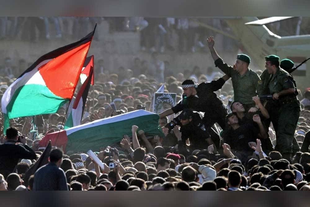 Pasukan keselamatan Palestin membawa keranda Yasser Arafat ketika jenazahnya dikembalikan ke Ramallah untuk dikebumikan pada 12 November 2004.