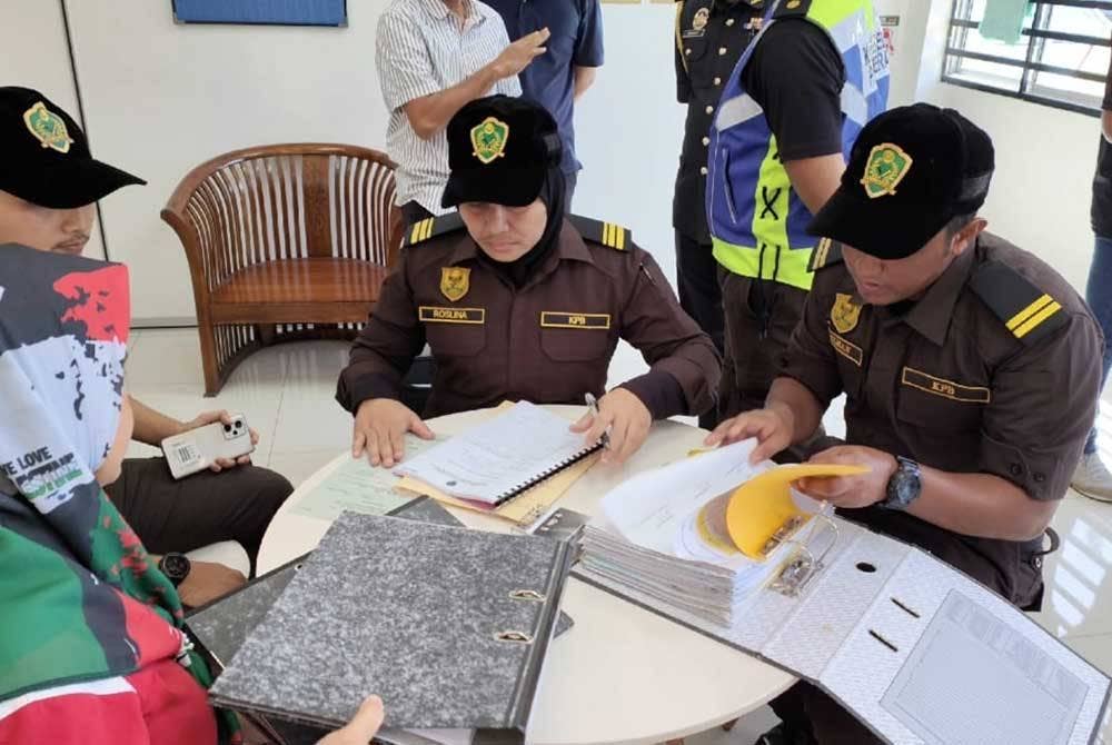 Pegawai KPB memeriksa dokumen ketika menjalankan operasi di kilang beras Mumtaz Iman di Indera Mahkota pada Isnin.