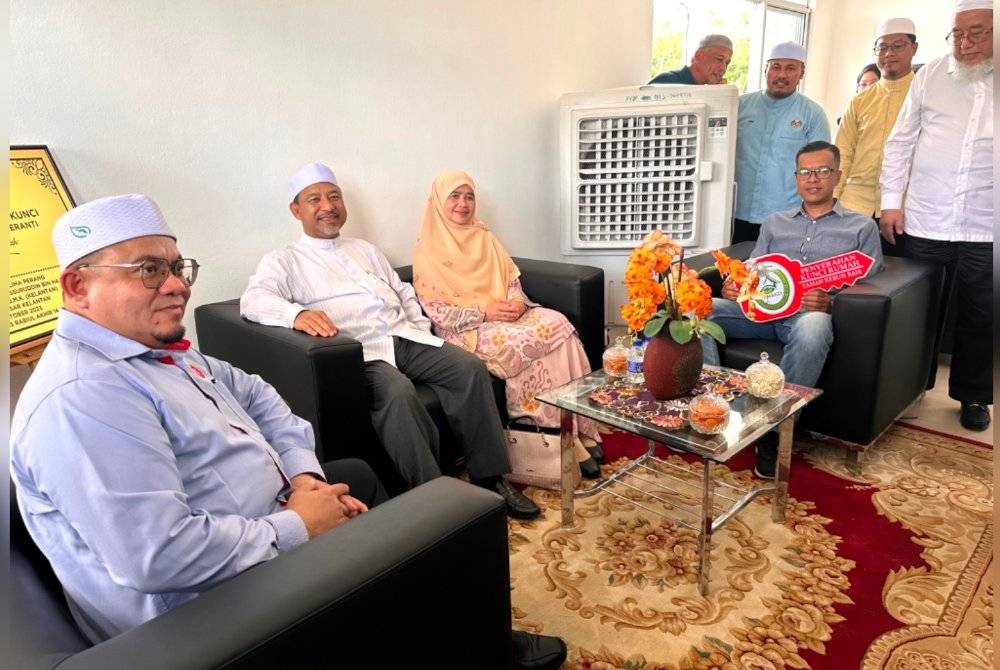 Mohd Nassuruddin (dua dari kiri) dan diiringi Hilmi (kiri) duduk dan melihat keadaan dalaman RMMK di Meranti, Pasir Mas.