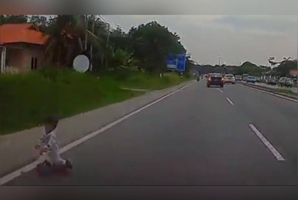 Tangkap layar daripada video tular memaparkan seorang kanak-kanak bermain di tepi jalan raya dan hampir dilanggar sebuah kenderaan di Kampung Semarang, Dengkil, Selangor pada Isnin.