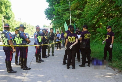 Polis mengumpul bukti di sebelah mayat di tempat kejadian tembakan di luar pusat mengundi di bandar Datu Odin Sinsuat di pulau Mindanao pada Isnin. - Foto AFP