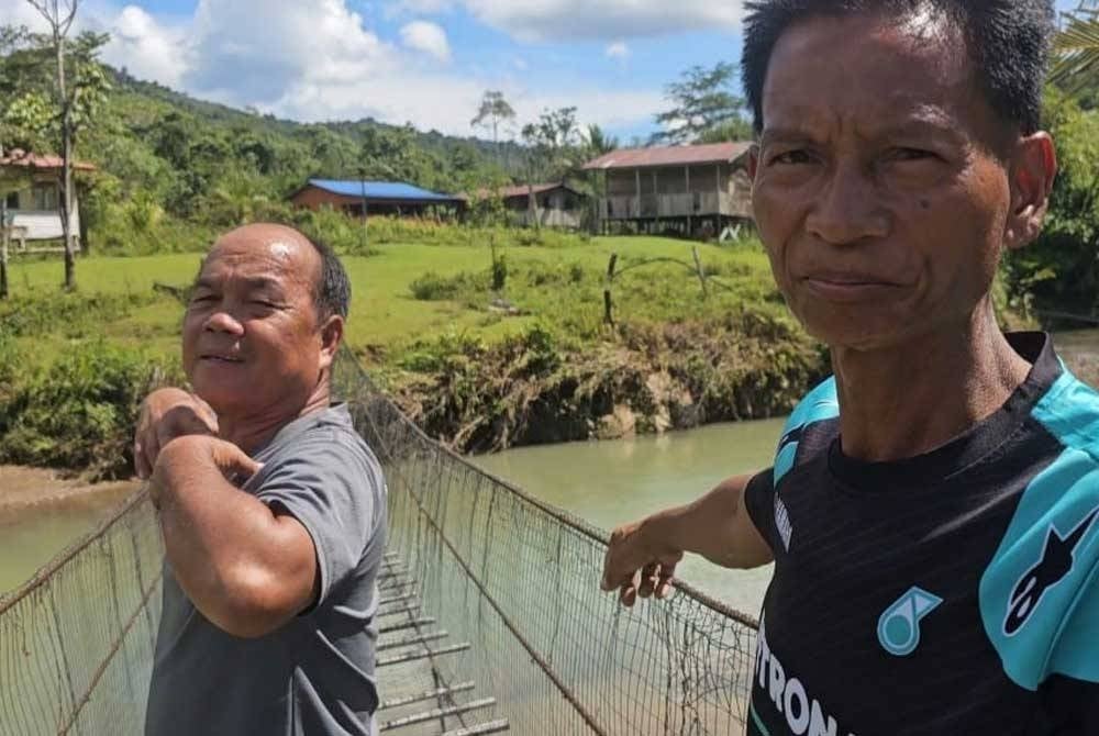 Rainis (kanan) dan Sangut menunjukkan keadaan jambatan gantung digunakan penduduk Kampung Saliliran yang reput dan tidak selamat untuk digunakan.