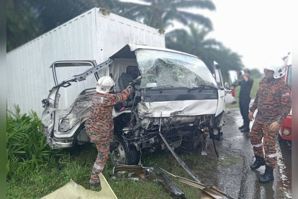 Pasukan bomba berusaha mengeluarkan pemandu lori yang tersepit.