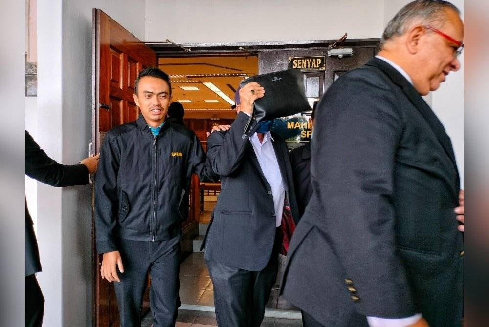 Muhammad Muhaimin (tengah) ketika keluar dari Mahkamah Seksyen Melaka pada Jumaat.