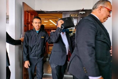 Muhammad Muhaimin (tengah) ketika keluar dari Mahkamah Seksyen Melaka pada Jumaat.
