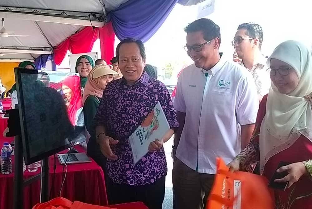 Ahmad Maslan (kiri) bersama Mohd Redzuan (tengah) dan Hasrunizah (kanan) melawat reruai sempena Program Takaful Masuk Kampung di Dewan Homestay Kampung Puteri Menangis, Ayer Baloi pada Sabtu.