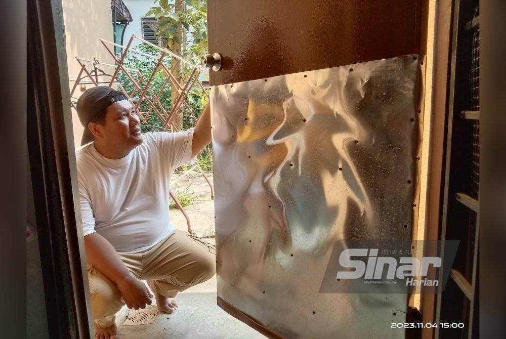 Mohamad Aris menunjukkan pintu bahagian dapur yang diumpil penjenayah.