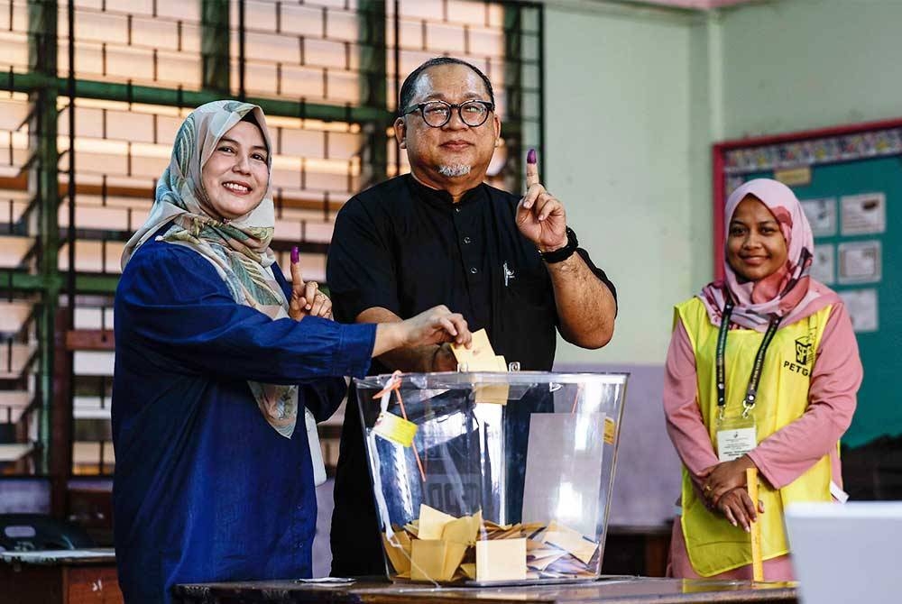 Iskandar (tengah) bersama isteri, Dayang Loha Awang Sahari mengundi di Pusat Mengundi Sekolah Kebangsaan Bintulu hari ini. - Foto Bernama