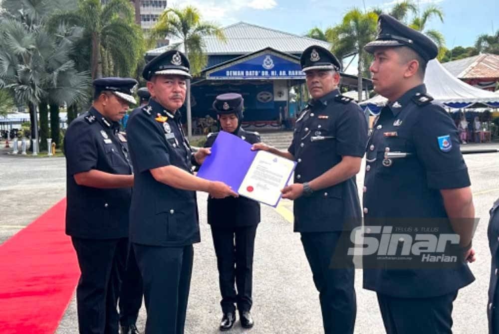 Muhamad Zaki (kiri) menyampaikan sijil kepada Inspektor Azman A Radzi (dua dari kanan) dari Cawangan Siasatan, Perundangan, Bahagian Siasatan dan Penguatkuasaan Trafik, Ibu Pejabat Polis Daerah Gua Musang di IPK pada Ahad.