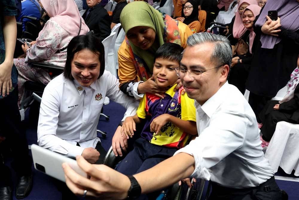 Fahmi melayan karenah pengunjung sambil berswafoto ketika menghadiri Majlis Perasmian Program Pemerkasaan OKU Celik Digital di Pusat Komuniti IWK Eco Park hari ini. - Foto Bernama
