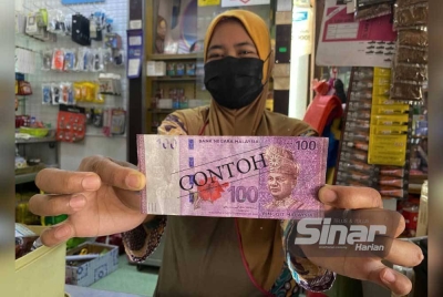 Noor Azizah menunjukkan duit RM100 palsu yang diterimanya.