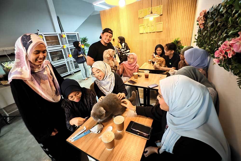 Muhammad Syafiq (empat dari kiri) dan Nazatul Faseha (kiri) melayan pelanggan yang datang ke kedainya.