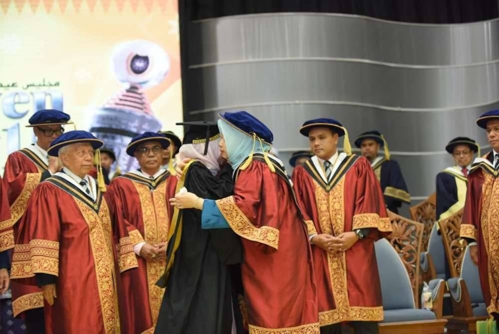 Haslina (tiga dari kanan) kelihatan sedih semasa mengambil skrol sambil dipeluk Dr Syarilla Iryani, selepas menerima berita kematian bapanya pada Majlis Konvokesyen Universiti Sultan Zainal Abidin (UniSZA) Ke-15, Kampus Gong Badak, pada Isnin.