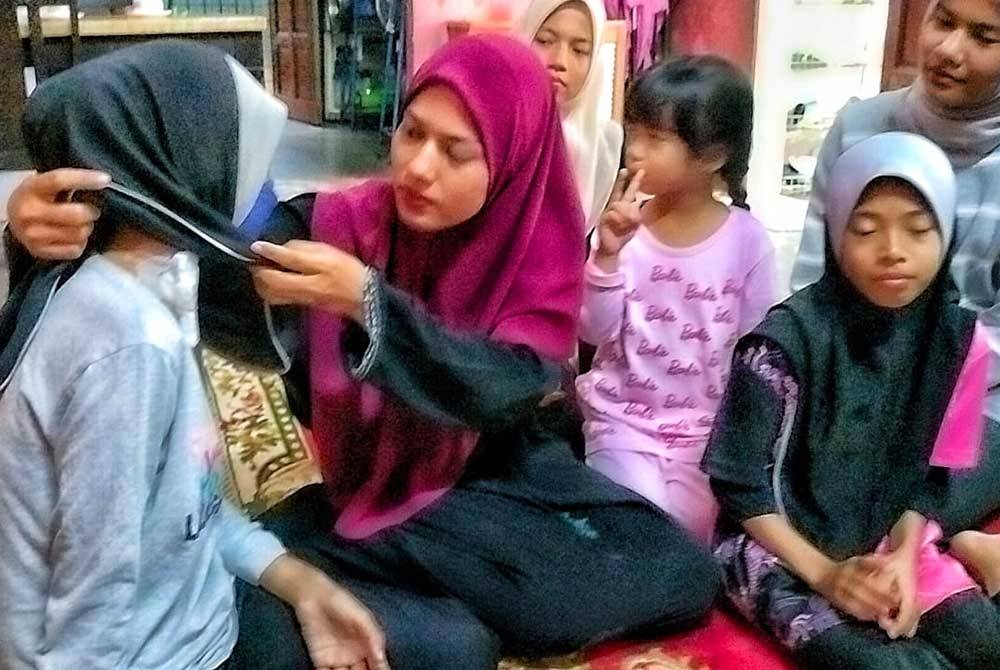 Fasehha (dua dari kiri) menunjukkan tapak kateter di leher Nur Najihah bagi melakukan rawatan dialisis.