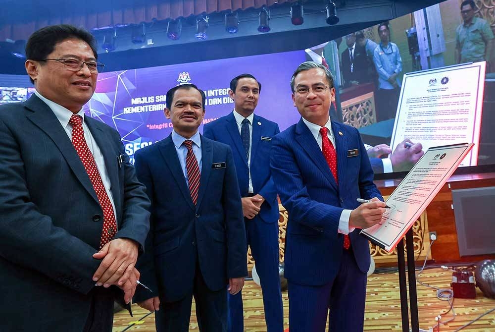 Menteri Komunikasi dan Digital, Fahmi Fadzil menandatangani Ikrar Bebas Rasuah sambil disaksikan oleh Azam (kiri) pada majlis sambutan Hari Integriti Kementerian Komunikasi dan Digital (KKD) bertemakan 'Integriti Citra Malaysia Madani' di KKD,pada Selasa. - Foto Bernama