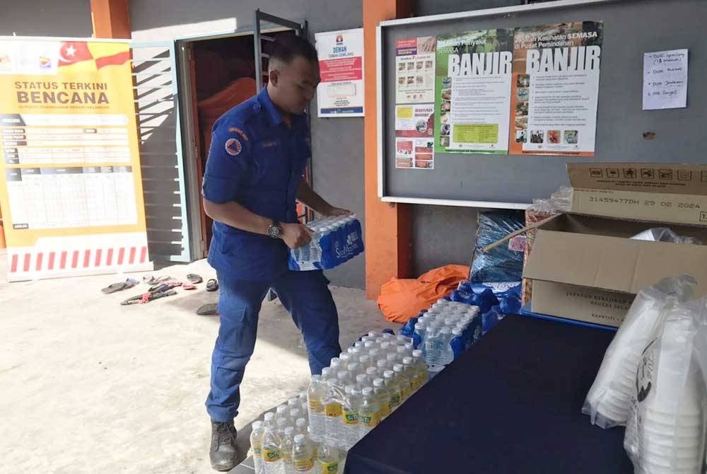 Anggota Angkatan Pertahanan Awam (APM) mengangkat minuman untuk diagihkan kepada mangsa banjir di sebuah PPS dekat sini pada Rabu.