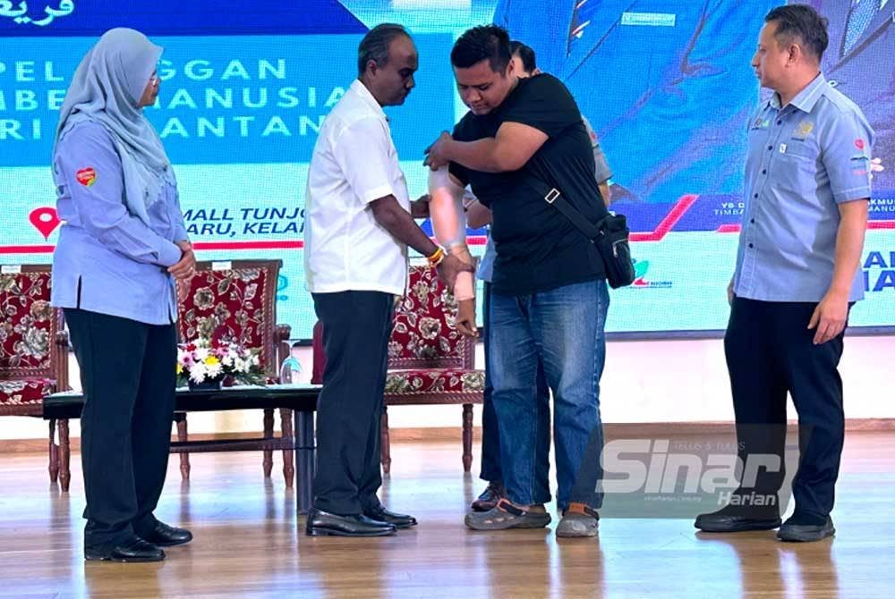 Sivakumar (dua dari kiri) membantu Mohamad Amiruddin (dua dari kanan) memakai tangan palsu pada Hari Bertemu Pelanggan Peringkat Negeri Kelantan di Mydin Mall Tunjong, Kota Bharu pada Rabu. - FOTO SINAR HARIAN