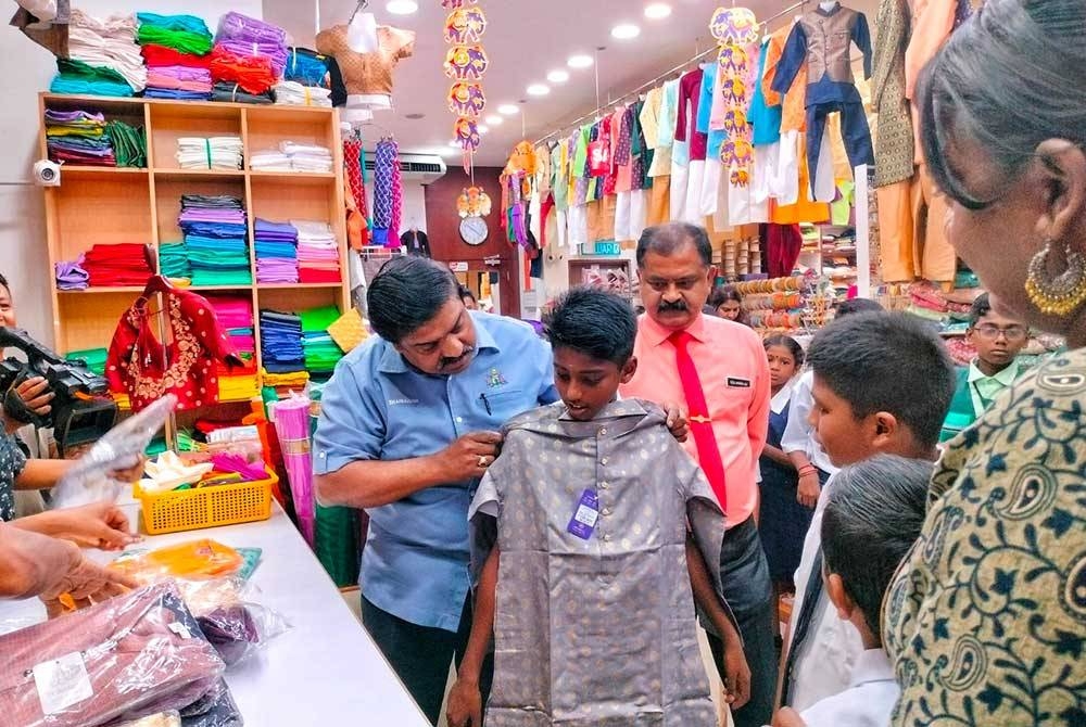 Shanmugam (kiri) membantu seorang pelajar memilih baju di Little India, Jalan Bendahara di sini, pada Rabu.