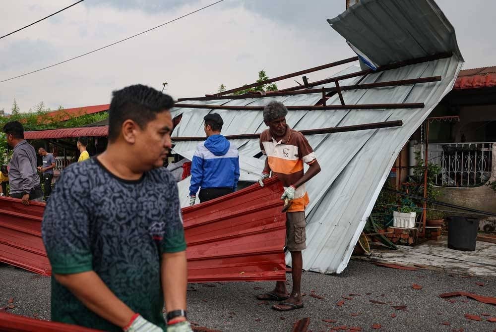 Penduduk melakukan kerja-kerja membersihkan kawasan perumahan selepas beberapa rumah rosak akibat kejadian ribut yang melanda kawasan perumahan mereka di Taman Klebang jaya hari ini. - Foto Bernama
