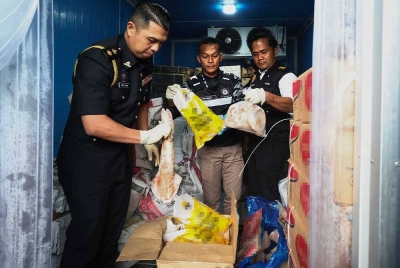 Azdy Zukkry (kiri) dan Pegawai Kesihatan Persekitaran Pejabat Kesihatan Kawasan Sandakan, Ts. Sundusin Nganro (kanan) melihat daging babi dan ayam yang bercampur dalam sebuah kontena sewaktu operasi bersepadu bersama Jabatan Perkhidmatan Veterinar dan Kementerian Kesihatan di sebuah premis, pada Rabu. - Foto Bernama
