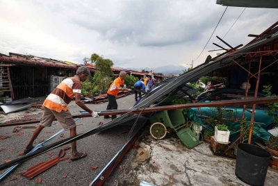Penduduk melakukan kerja-kerja membersihkan kawasan perumahan selepas beberapa rumah rosak akibat kejadian ribut yang melanda kawasan perumahan mereka di Taman Klebang jaya hari ini. - Foto Bernama