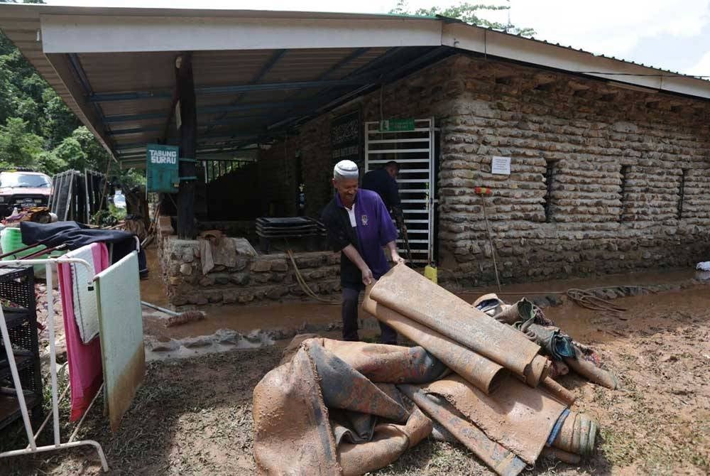 Penduduk membersihkan surau di tapak perkhemahan di Kem Sungai Batu yang ditenggelami kepala air, dekat Sintok pada Rabu.