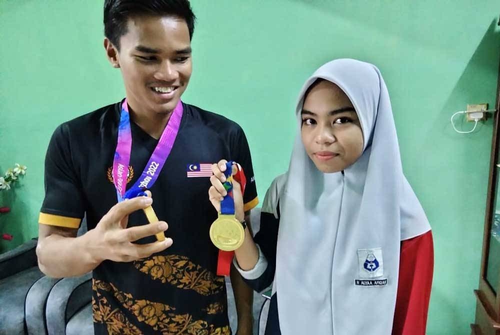 Nurul Alyaa (kanan) menunjukkan pingat emas Sukan Sukan Para Asia Hangzhou dimenangi abangnya Ammar Aiman.