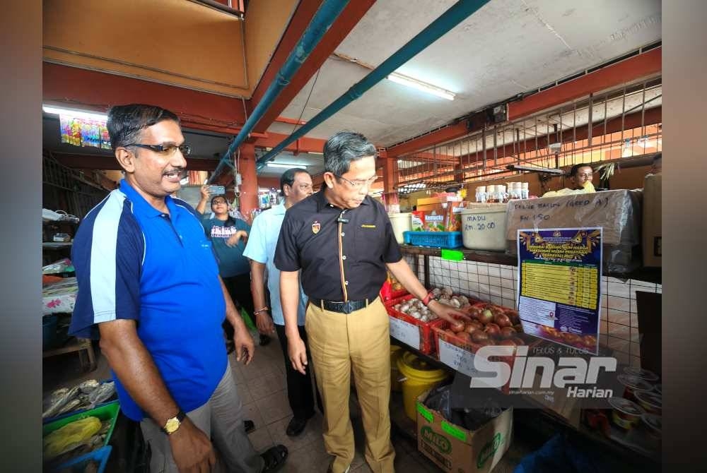 Jalaluddin (dua dari kiri) melihat harga bawang besar yang dijual di Pasar Awam Simpang Pertang.