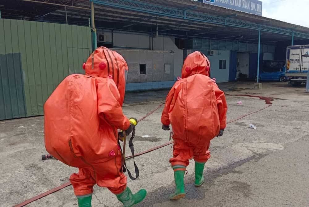 Pasukan bomba memakai pakaian perlindungan diri (PPE) sebagai langkah keselamatan.