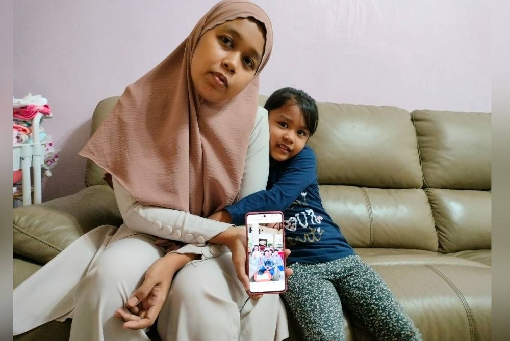 Nastasha Aidura (kiri) menunjukkan gambar arwah suaminya bersama anak keempat, Nur Ariana Raisha yang berusia empat tahun