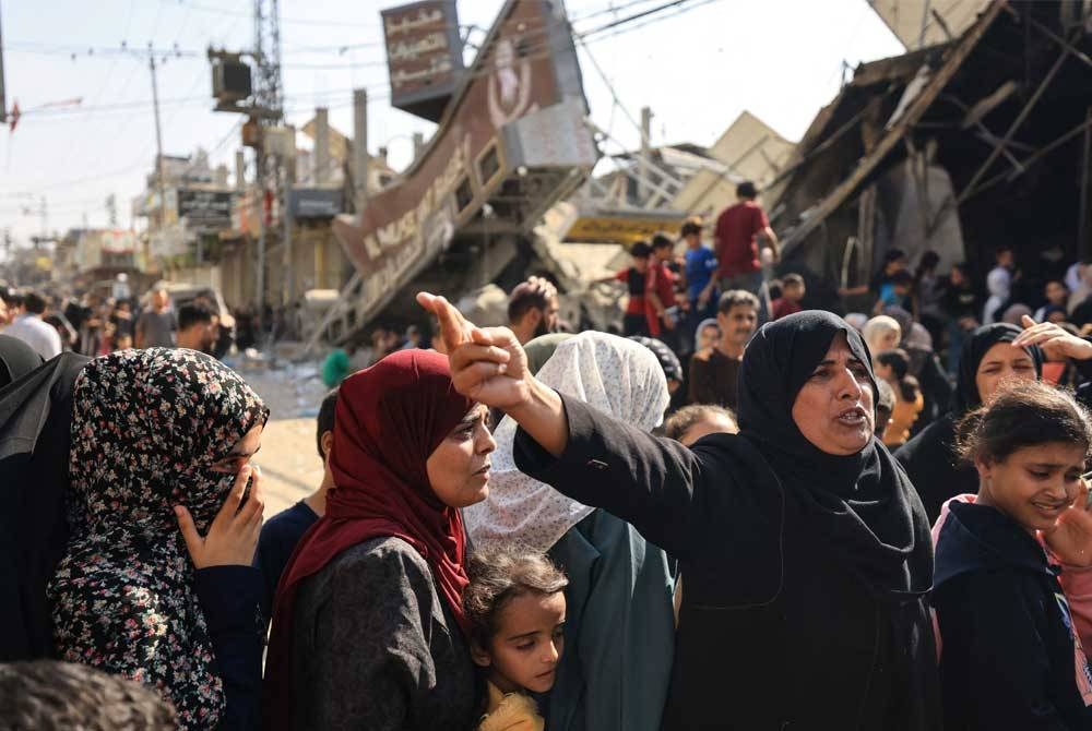 Penduduk Gaza berbaris panjang di hadapan kedai roti yang musnah di kem Nuseirat kerana masih terdapat bekalan roti yang diagihkan kepada orang ramai. -AFP