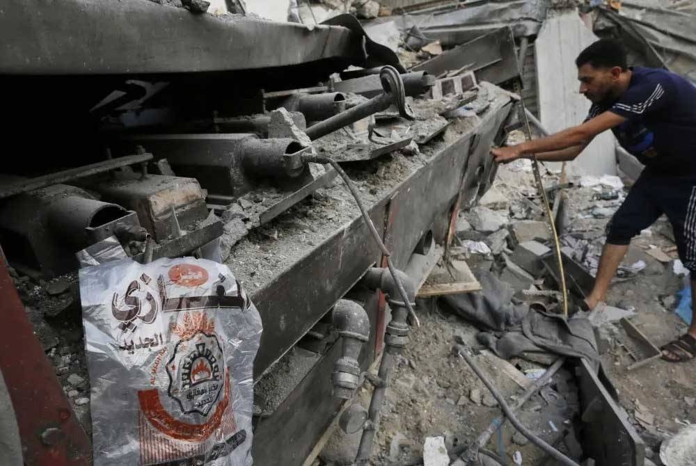 Seorang pekerja melihat bahagian dapur sebuah kedai roti yang dibedil roket Israel di utara Gaza. - Agensi