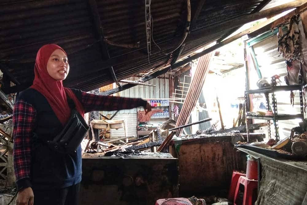 Nur Ayu Nazira menunjukkan keadaan gerainya yang musnah.