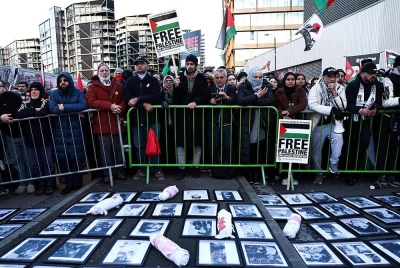 Penunjuk perasaan memegang sepanduk dan bendera di sekeliling tugu peringatan sementara dengan gambar mangsa pengeboman di Gaza, semasa 'Perarakan Kebangsaan Untuk Palestin' di tengah London pada Sabtu. - Foto: AFP