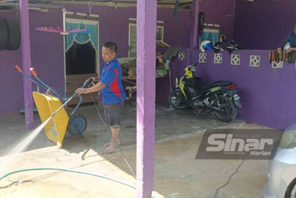 Mohamad Razak membersihkan pekarangan rumahnya di Kampung Sentosa Damai, Pasir Gudang pada Isnin selepas dibenarkan pulang dari PPS.