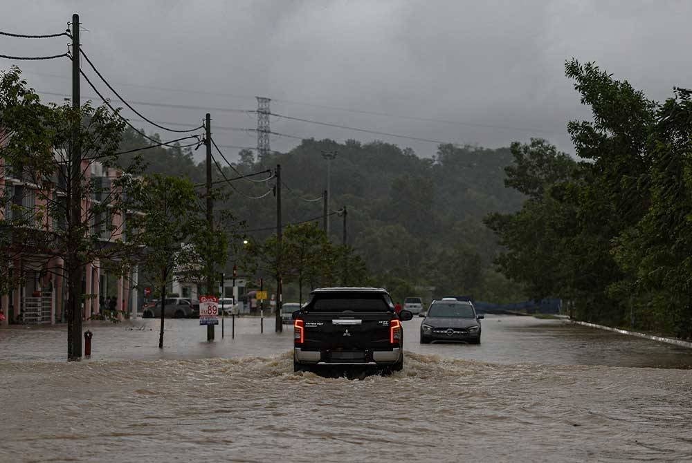 Kenderaan pacuan empat roda melintasi jalan yang dinaiki air ketika tinjauan di Meru Raya hari ini. - Foto Bernama