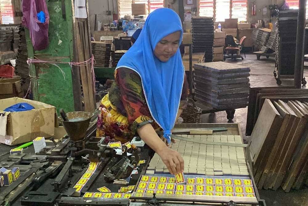 Pekerja sedang menyusun kotak mancis yang siap digam.