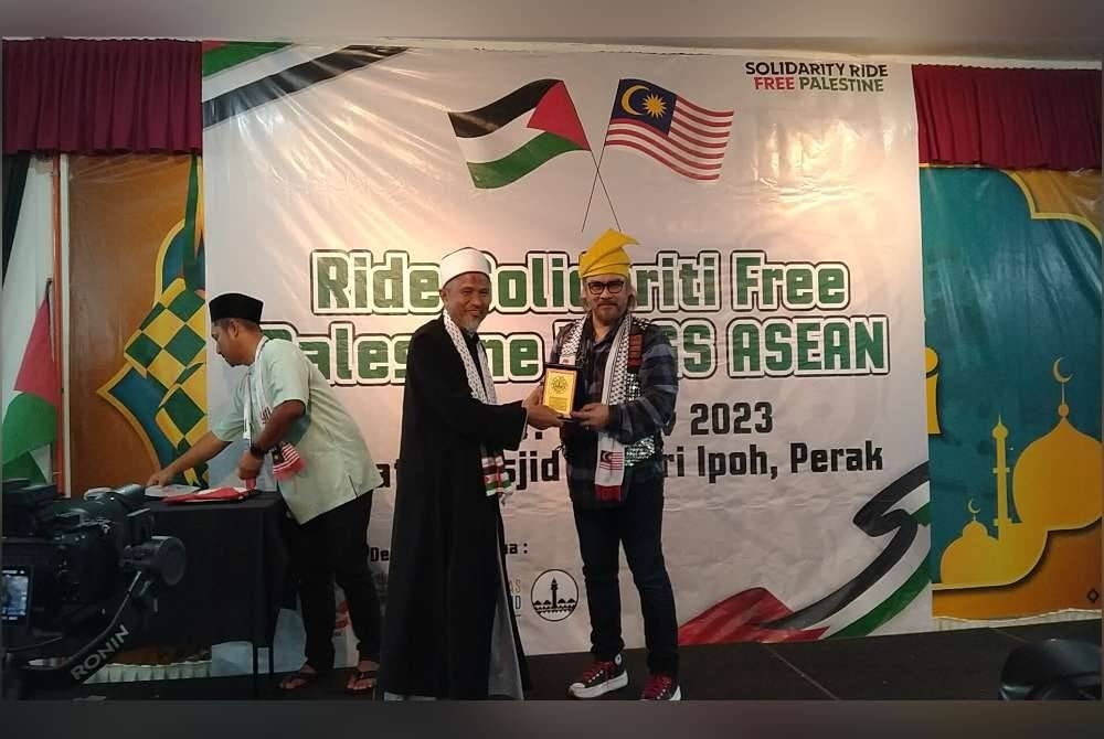 Awie (kanan) menerima cenderahati daripada Ridzuan sempena program Solidarity Ride Free Palestine WMGS Asean ke Masjid Negeri Perak di Masjid Sultan Idris Shah II di sini pada Isnin.