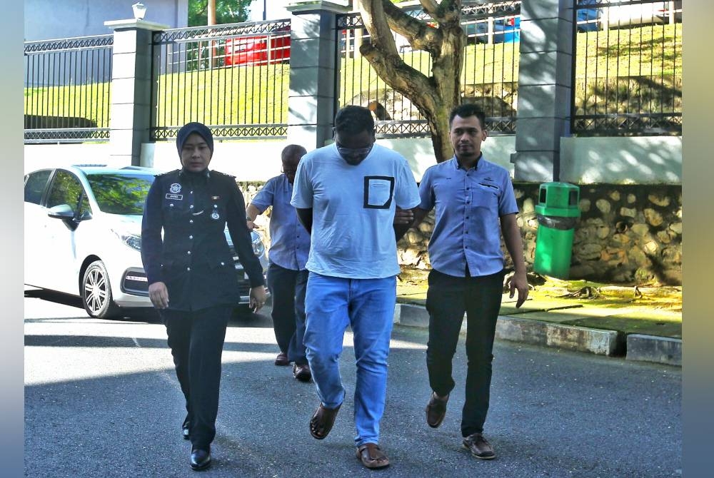 Manimaran (tengah) diiringi polis ketika hadir di mahkamah.