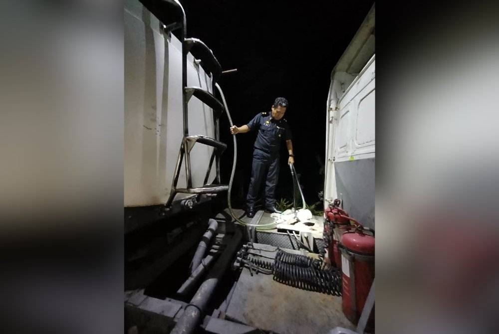 Penguat kuasa KPDN memeriksa lori tangki yang diubah suai bagi mengisi minyak diesel bersubsidi ketika serbuan di sebuah stor tersembunyi di sini pada Selasa.