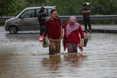 Penduduk D'Aman Meru Raya melintasi jalan yang dinaiki air ketika tinjauan di Meru Raya. - Foto Bernama