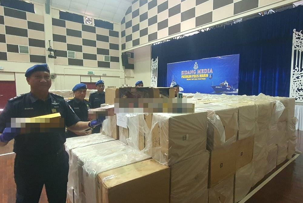 Shamsol (kiri) menunjukkan sebahagian rokok putih yang dirampas dalam satu serbuan di George Town.