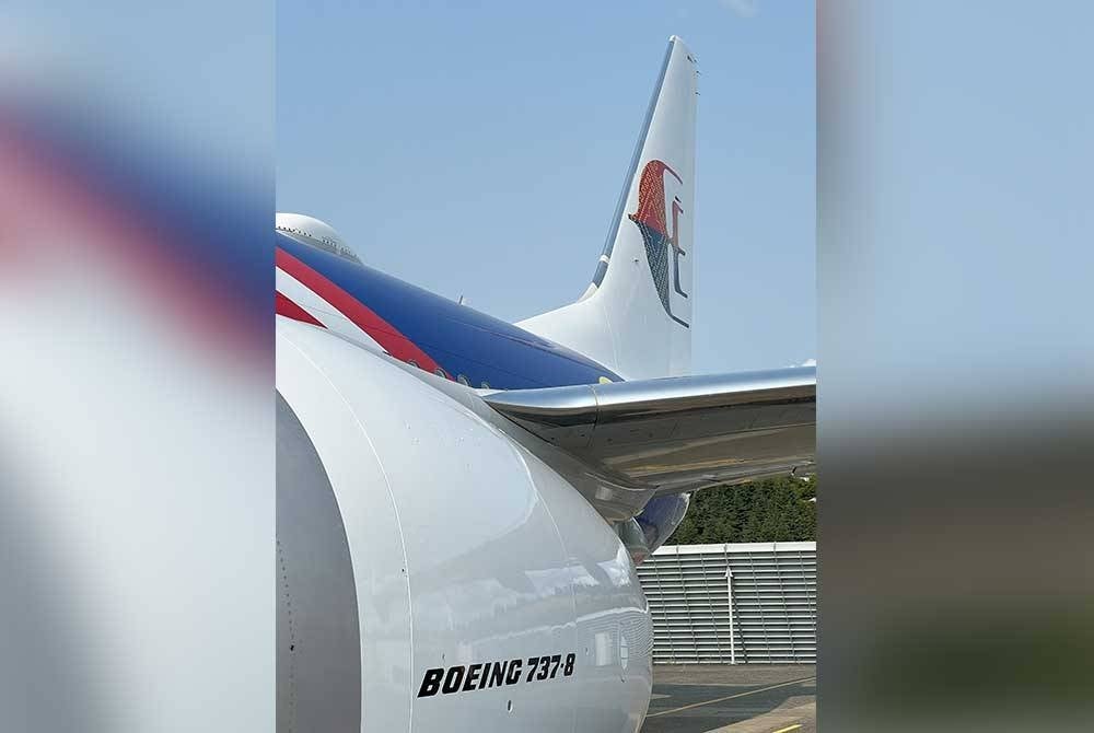 Logo ikonik 'wau' pada badan pesawat yang dihiasi dengan motif songket berwarna emas.