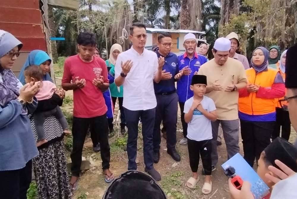 Mohd Fared (tengah) mengaminkan bacaan doa setelah pasangan suami isteri yang tinggal di pondok usang bersetuju untuk berpindah.