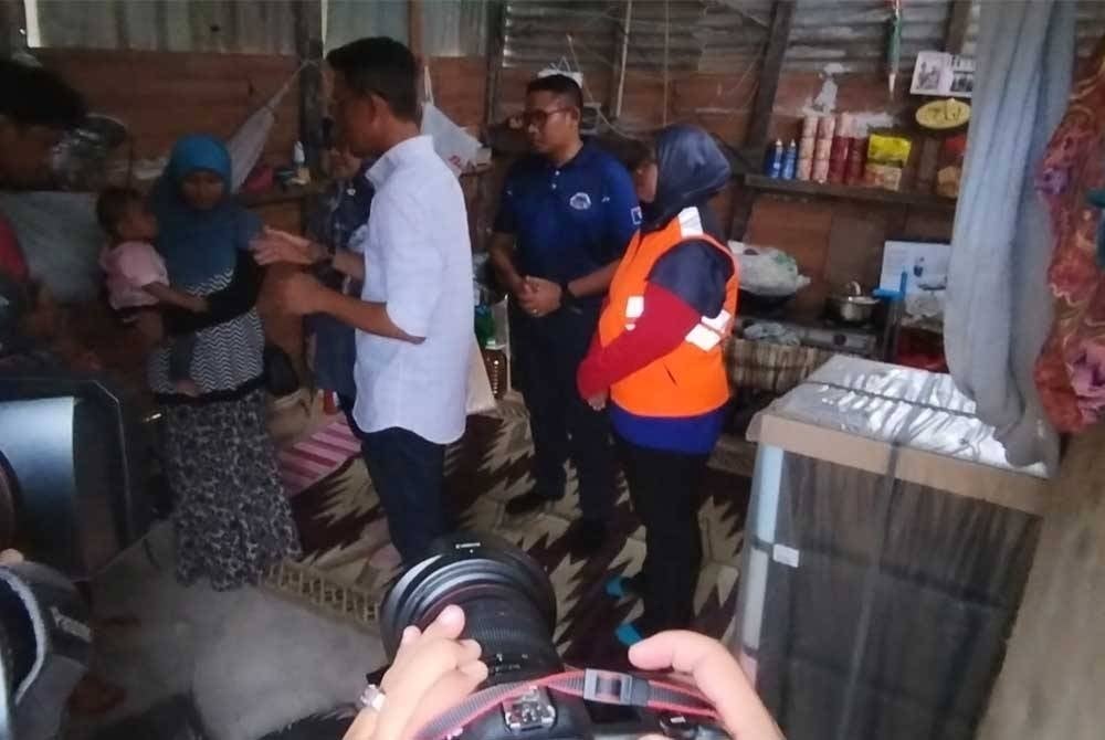 Mohd Fared (tengah) meninjau kawasan rumah pasangan suami isteri di Kampung Baharu Ulu Sungai Johor, Kota Tinggi.