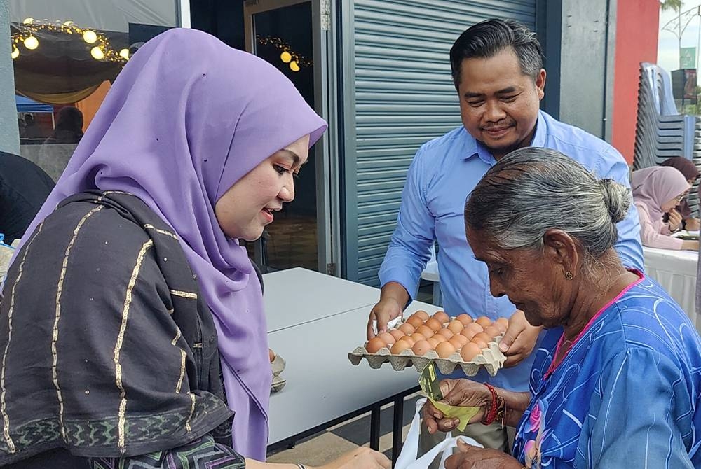 Nurul Syazwani (kanan) menyampaikan sumbangan kepada salah seorang penerima.